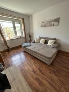a large couch in a living room with a wooden floor at Gemütlich wohnen in Blankenstein am Rennsteig 