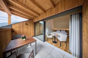 a room with a balcony with a table and a bedroom at Hotel Schmuckhof in Chiusa