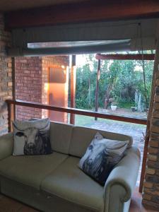 a couch with two pillows on it in a living room at Bush Beach Safari Accommodation in Jeffreys Bay