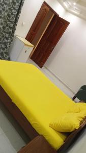 1 cama con sábanas amarillas en una habitación en Logement Kabrousse, en Saly Portudal