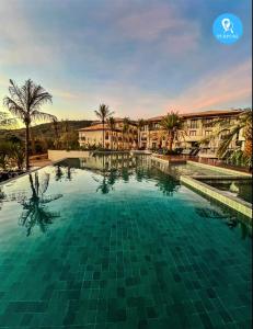 a large swimming pool with palm trees and buildings at Pyrenéus Residence in Pirenópolis