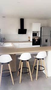 a kitchen with two white bar stools and a counter at Jolie maison, plain-pied à Dole in Dole