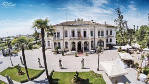 a large white building with palm trees in front of it at Villa Ducale Hotel & Ristorante in Dolo