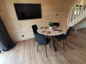 a dining room with a table and chairs and a flat screen tv at Hortensja 2 in Rusinowo