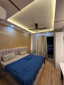 une chambre avec un grand lit avec une couverture bleue dans l'établissement Velvet Vista, à Greater Noida