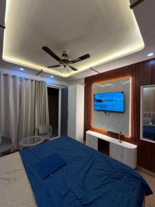 une chambre avec un lit bleu et une télévision à écran plat dans l'établissement Velvet Vista, à Greater Noida