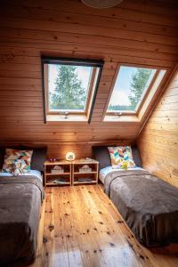 two beds in a log cabin with two windows at Dom Marzeń z jacuzzi pod gwiazdami in Kopalino