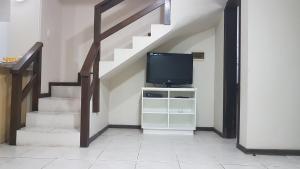 un soggiorno con scala, TV e stand TV di Casa perto da praia - Frente para Lagoa a Garopaba