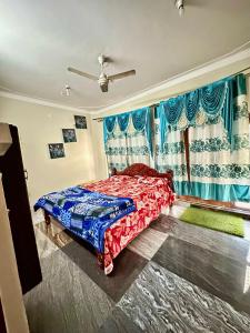 a bedroom with a bed and a window with blue curtains at Green Mysore 2BHK Apartment 1km from railway station in Mysore