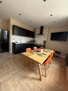 a dining room table with orange chairs and a kitchen at Stylish and Bright 2 Bedroom Flat Free Parking in Wallasey