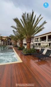 a pool with two chairs and a palm tree on a deck at Pyrenéus Residence in Pirenópolis