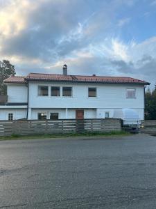 a white house with a fence in front of it at Cozy apartment close to the city center and mountains in Tromsø