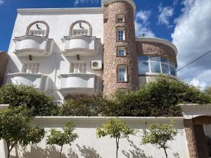 a building with a tower with windows and bushes at Appartement de plage d in As Suwaysah