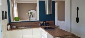 a kitchen with white cabinets and a blue wall at Grand gîte 15 personnes, 9 chambres, 100km de Paris en Exclusivité in Septmonts +123 photos