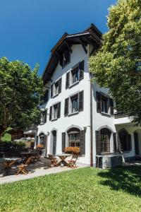 een wit gebouw met picknicktafels ervoor bij Hotel Sanetsch in Gsteig