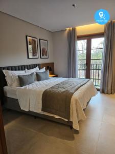 a bedroom with a large bed and a balcony at Pyrenéus Residence in Pirenópolis