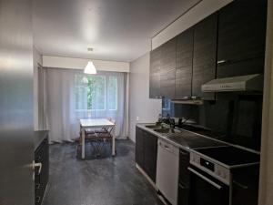 a kitchen with black cabinets and a table and a window at Myllymäki 22 X in Lahti