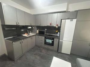 a kitchen with white cabinets and a refrigerator at Нощувки Шумен in Shumen