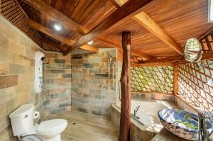 a bathroom with a toilet and a bath tub at Samara Tarantela, Treehouse in Sámara +15 photos