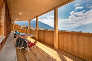 a room with a balcony with a table and chairs at Das Moriggl in Malles Venosta