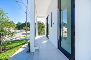Una vista exterior de una casa blanca con puertas de vidrio. en Luxe Pool House in North Miami Perfect for Groups, en North Miami Beach