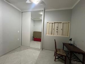 a room with a mirror and a desk and a bedroom at CASA Vila Braz - Pirassununga, SP in Pirassununga
