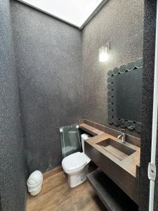 a bathroom with a toilet and a sink and a mirror at CASA Vila Braz - Pirassununga, SP in Pirassununga
