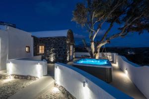 a backyard with a hot tub and a tree at night at Red beach Harmony Suites Stone house in Akrotiri