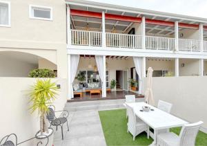 an outdoor patio with a white table and chairs at Coastal Bliss Getaway Awaits! in Keurboomstrand