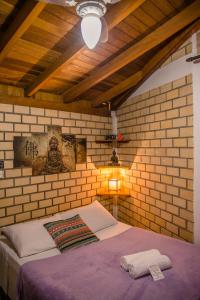 a bedroom with a bed in a brick wall at Morada Quatro Elementos - 150 Metros do Centrinho in Praia do Rosa