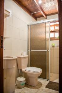 a bathroom with a toilet and a glass shower at Morada Quatro Elementos - 150 Metros do Centrinho in Praia do Rosa +59 photos