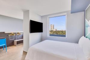a white bedroom with a bed and a window at One Ciudad Juarez Alameda Iglesias in Manuel F. Martínez