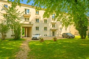 a large white building with two cars parked in a yard at WILSON PREMIUM suites in Nitra