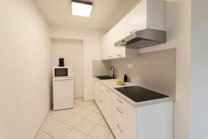 a white kitchen with a sink and a refrigerator at WILSON PREMIUM suites in Nitra