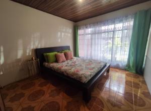 a bed in a room with a window and a bed with pillows at Casa Victoria in San José