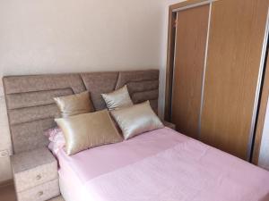 a bedroom with a bed with pink sheets and pillows at Très joli appartement vue sur parc 5 min de la plage du centre mohammedia in Mohammedia