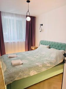 a bedroom with a green bed with two towels on it at Premium Apartment Turda in Turda