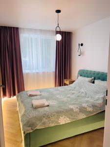 a bedroom with a green bed with two towels on it at Premium Apartment Turda in Turda