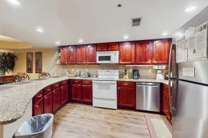 una cocina con armarios de madera y electrodomésticos blancos en Gatehouse Condos - Roaring Romance, en Gatlinburg 10 fotos más