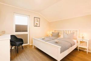 a bedroom with a white bed with a chair and a window at Traumvilla am Müritz Nationalpark, 17 Gäste, Sauna in Boek
