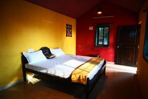 1 dormitorio con 1 cama con paredes rojas y amarillas en Koral Islands Homestay, en Sadāshivgarh