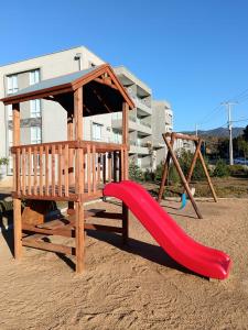 a playground with a red slide and a gazebo at Hermoso departamento, Punta Puyai, Papudo in Petorca
