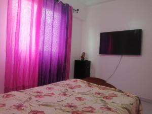 a bedroom with a bed with purple curtains and a tv at Hatime zarkaoui in Casablanca