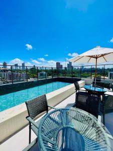 Un patio con mesa y sillas y una piscina. en Unu house Ondina, en Salvador