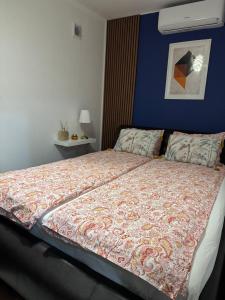 a bed in a bedroom with a blue wall at Apartman Alchemist I in Bosanska Dubica