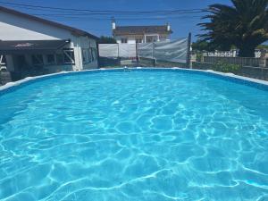 a large pool with blue water in front of a house at Villa Las Catedrales - Piscina Privada - Frente a la playa - Amplio jardín in Barreiros