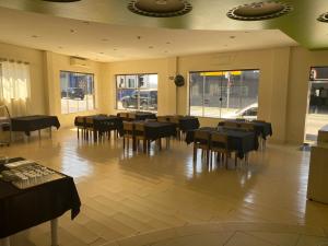 a restaurant with tables and chairs in a room with windows at Hotel Vitoria in Varginha