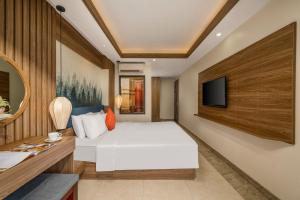 a bedroom with a white bed and a tv at NA Hotel Hoi An in Hoi An +21 photos