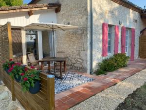 a patio with a table and an umbrella at Petit Rousset Gite Noyer in Eymet