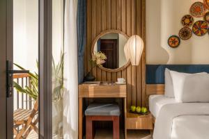 a bedroom with a bed and a mirror at NA Hotel Hoi An in Hoi An